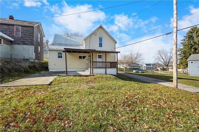 rear view of property with covered porch and a lawn