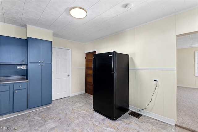 kitchen featuring black refrigerator, crown molding, blue cabinets, and light carpet