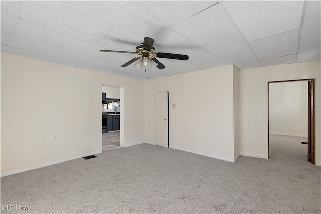 carpeted empty room with a drop ceiling and ceiling fan