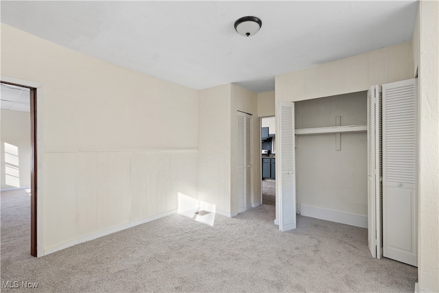 unfurnished bedroom with light colored carpet and multiple closets