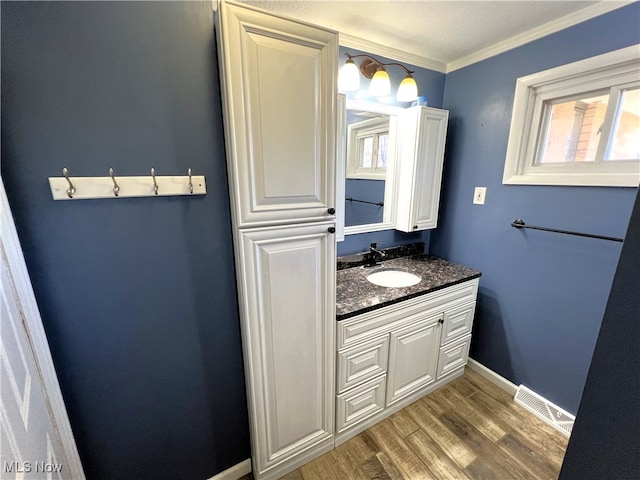 bathroom with hardwood / wood-style floors, vanity, a healthy amount of sunlight, and ornamental molding