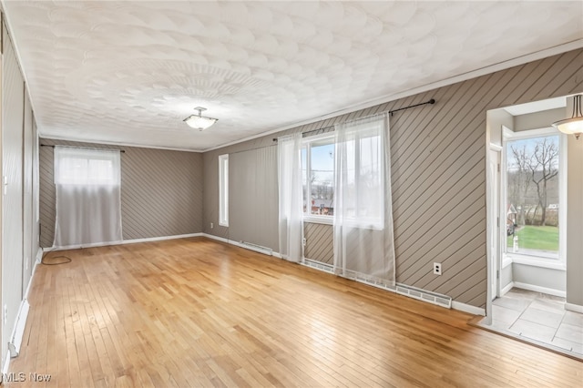 empty room with wood walls, light hardwood / wood-style floors, and crown molding