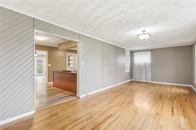 spare room with wood walls, wood-type flooring, and a healthy amount of sunlight