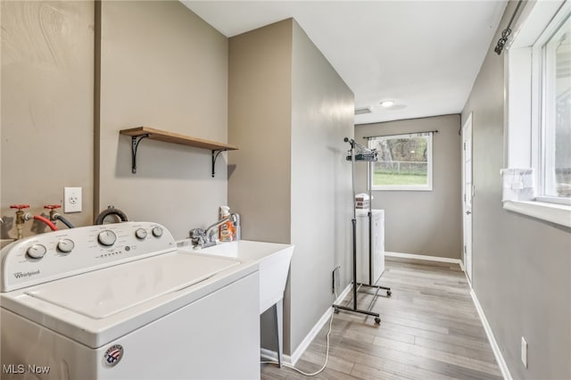 clothes washing area featuring washer / dryer and light hardwood / wood-style flooring