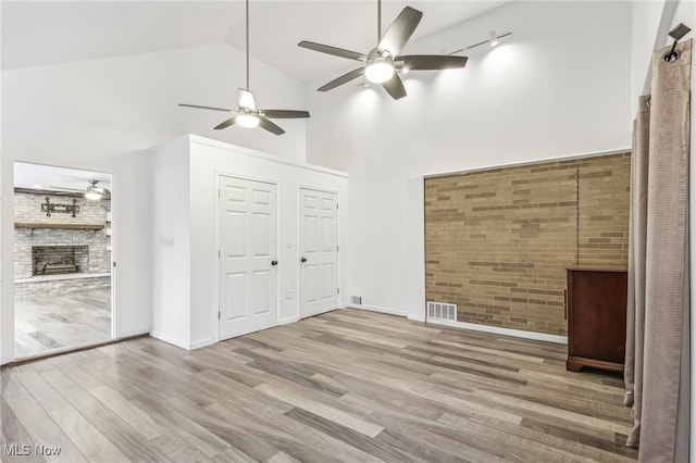 interior space featuring ceiling fan, brick wall, track lighting, and light wood-type flooring