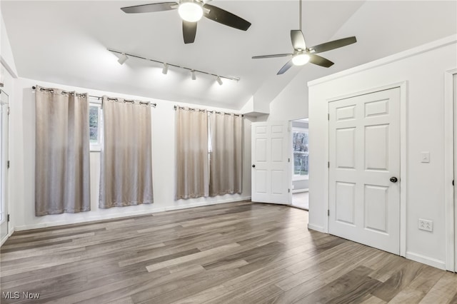 spare room featuring a wealth of natural light, track lighting, vaulted ceiling, and hardwood / wood-style flooring