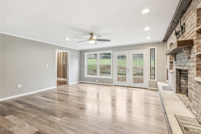 unfurnished living room featuring ceiling fan, light hardwood / wood-style floors, a fireplace, and french doors