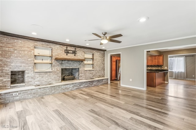 unfurnished living room featuring crown molding, ceiling fan, a fireplace, and light hardwood / wood-style floors