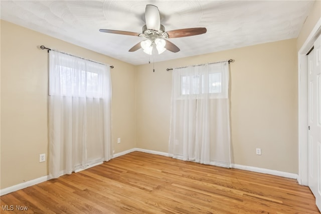 spare room with ceiling fan, light hardwood / wood-style floors, and a wealth of natural light