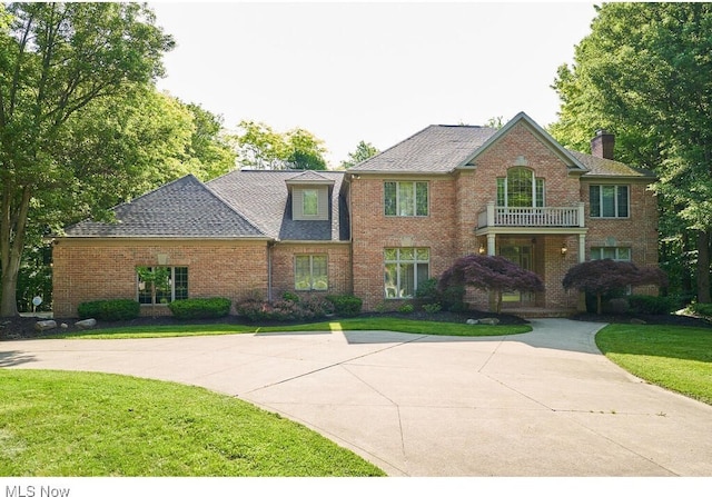 view of front of house with a balcony and a front yard