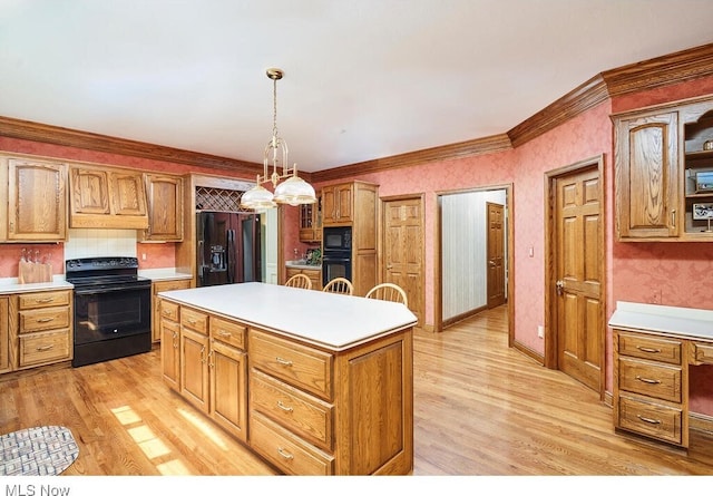 kitchen with crown molding, black appliances, pendant lighting, light hardwood / wood-style flooring, and a kitchen island