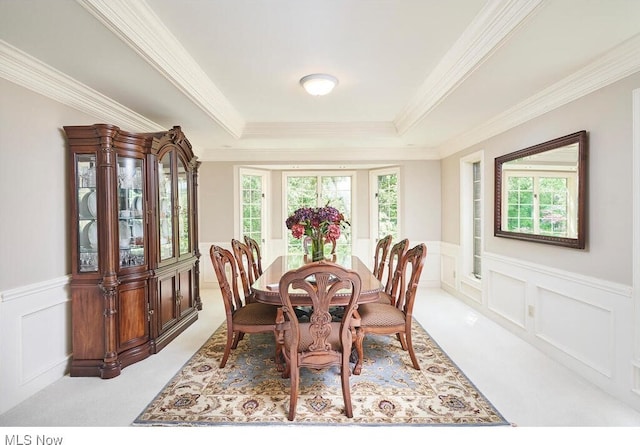 carpeted dining space featuring a healthy amount of sunlight, a raised ceiling, and crown molding