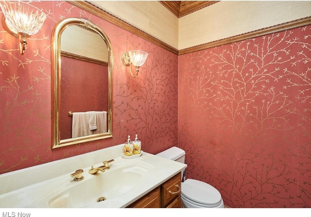 bathroom with toilet, vanity, and ornamental molding