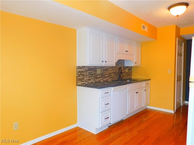 kitchen featuring white cabinetry, sink, tasteful backsplash, white dishwasher, and wood-type flooring