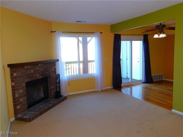 unfurnished living room with a wealth of natural light, a fireplace, ceiling fan, and hardwood / wood-style flooring