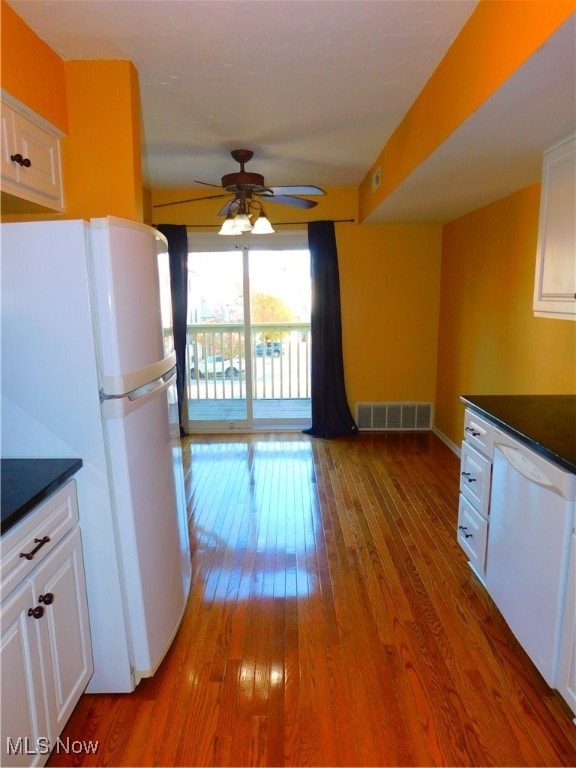 kitchen with ceiling fan, hardwood / wood-style floors, white cabinets, and white appliances