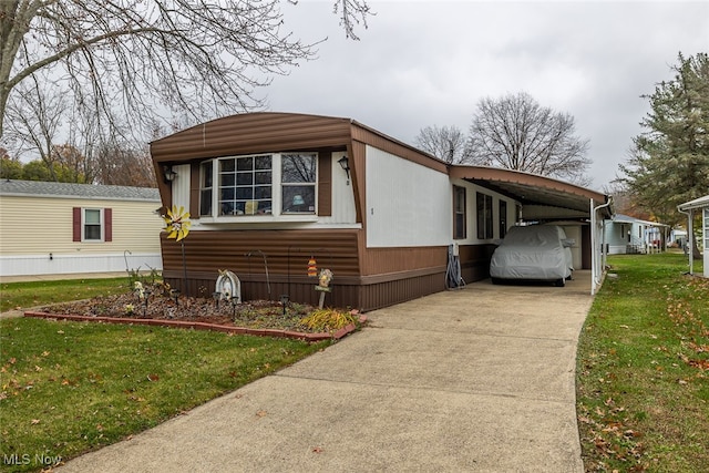 manufactured / mobile home featuring a front yard and a carport