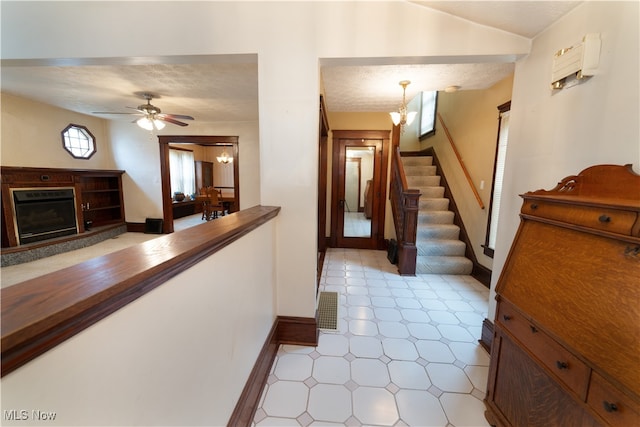 foyer entrance with visible vents, ceiling fan with notable chandelier, stairway, a fireplace, and baseboards