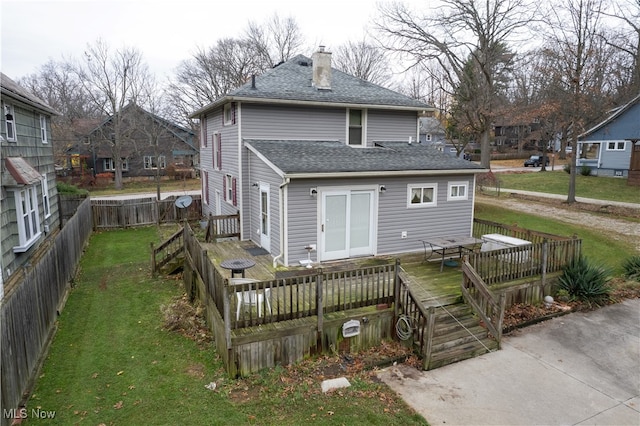 rear view of property with a shingled roof, fence, a chimney, a yard, and a deck