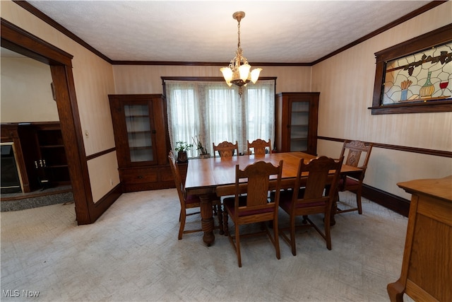 dining space with a textured ceiling, light colored carpet, an inviting chandelier, and ornamental molding