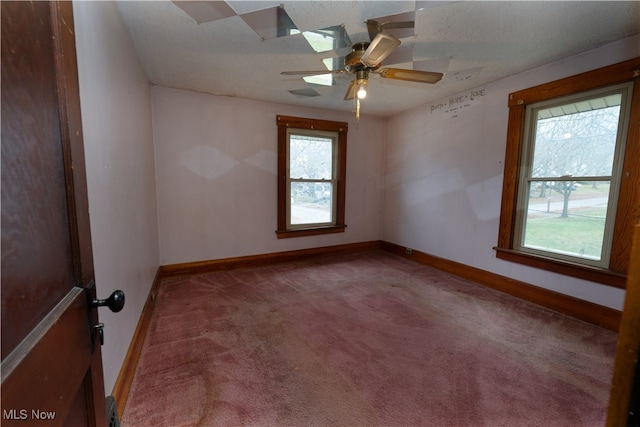 spare room featuring ceiling fan, plenty of natural light, carpet, and a textured ceiling