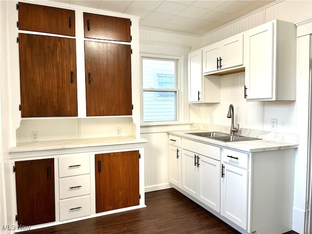 kitchen featuring dark hardwood / wood-style floors, white cabinetry, crown molding, and sink