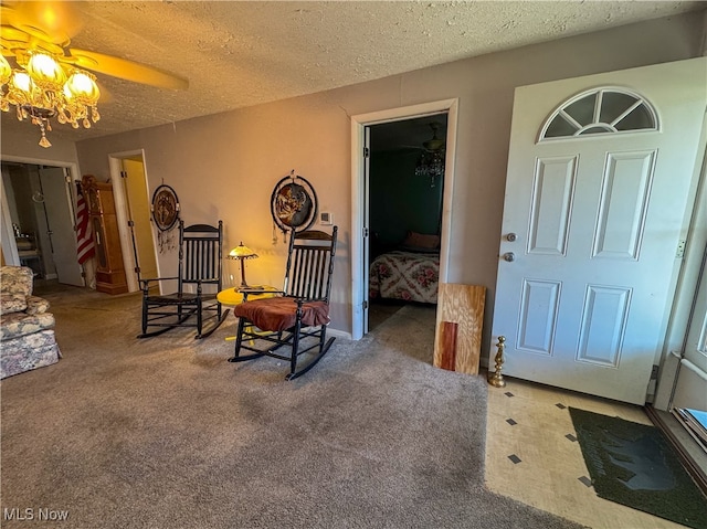 living area with carpet flooring, ceiling fan, and a textured ceiling