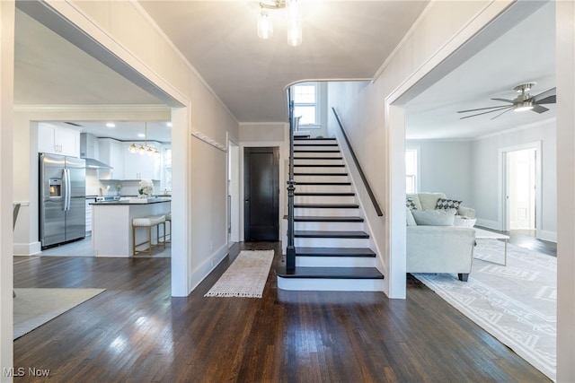 staircase with crown molding, ceiling fan, and wood-type flooring