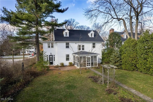 rear view of property with a lawn and a sunroom