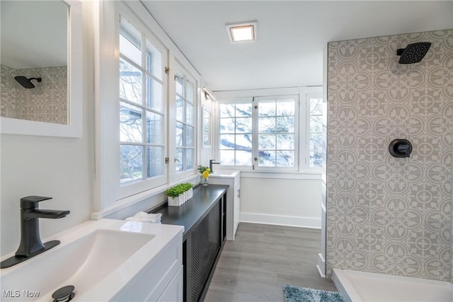 bathroom with a tile shower, vanity, a healthy amount of sunlight, and wood-type flooring