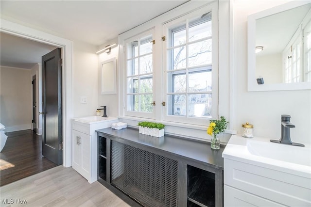 bar featuring sink, light wood-type flooring, and white cabinetry