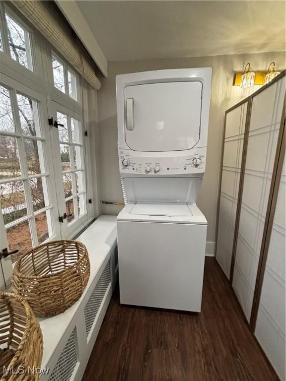 washroom with stacked washer / dryer, a wealth of natural light, and dark wood-type flooring