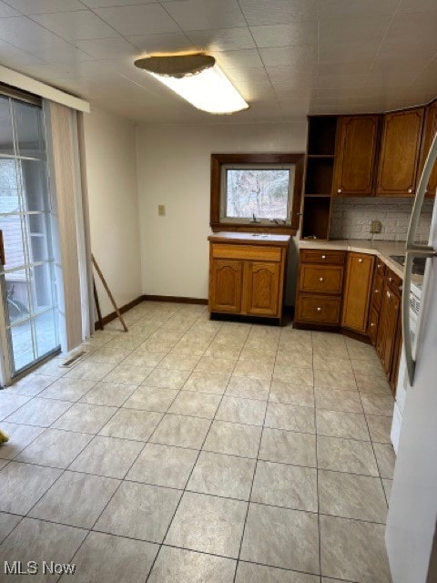 kitchen with tasteful backsplash, a wealth of natural light, light tile patterned floors, and white refrigerator