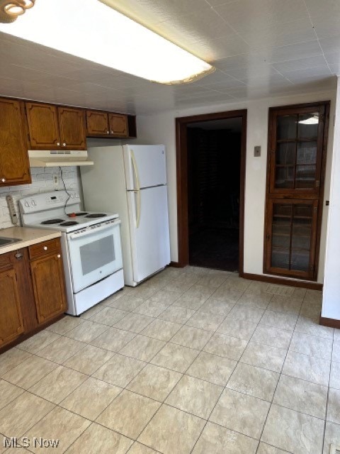 kitchen with decorative backsplash, light tile patterned floors, and white appliances