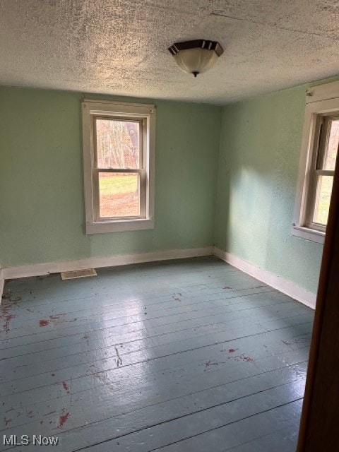 empty room with a textured ceiling, light hardwood / wood-style floors, and a healthy amount of sunlight