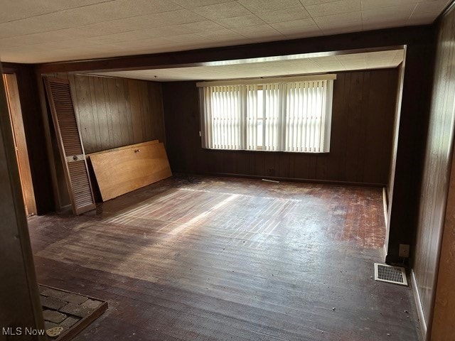 empty room with dark wood-type flooring and wooden walls