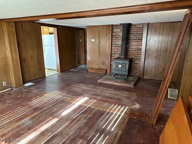 unfurnished living room featuring a wood stove, wood walls, dark hardwood / wood-style flooring, and heating unit