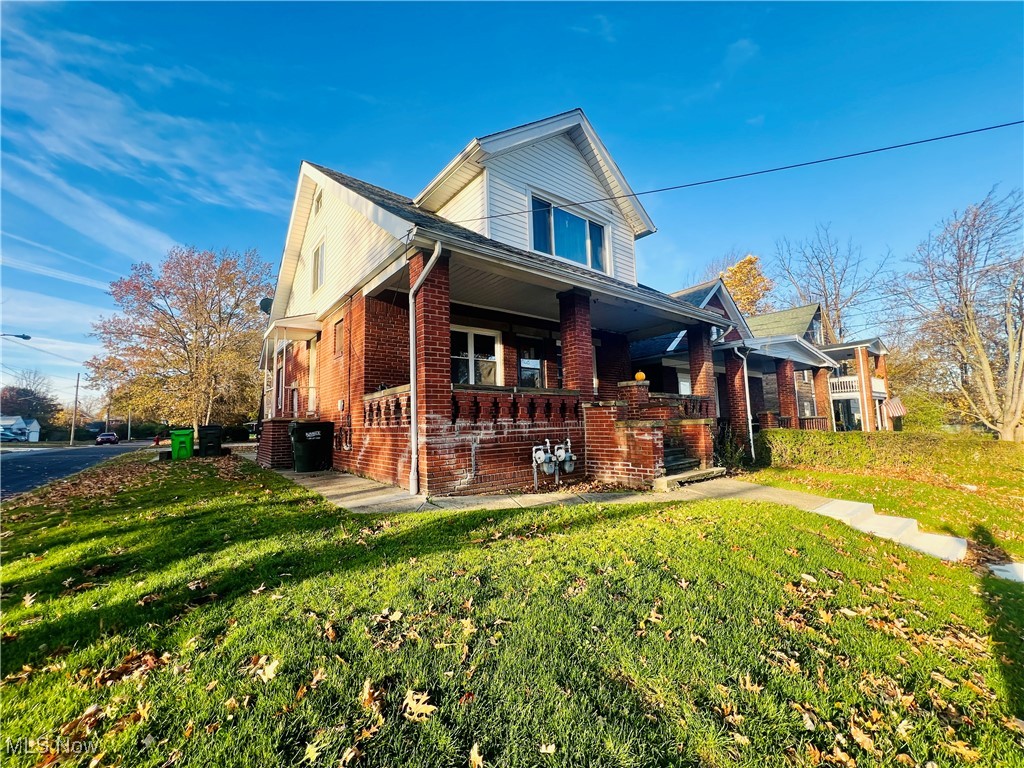 view of side of home with a porch and a yard