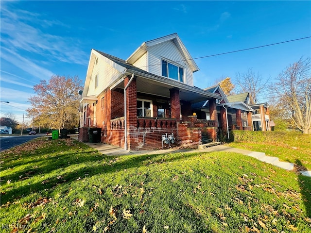 view of side of home with a porch and a yard