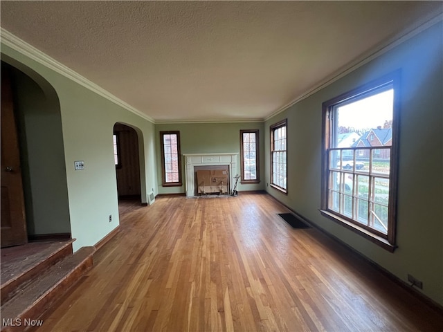 unfurnished living room featuring a textured ceiling, light hardwood / wood-style flooring, and crown molding