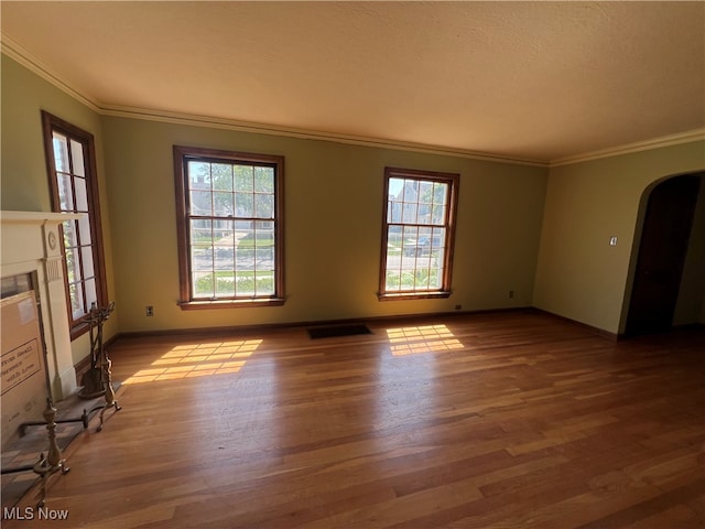 unfurnished living room with plenty of natural light, ornamental molding, and light hardwood / wood-style flooring