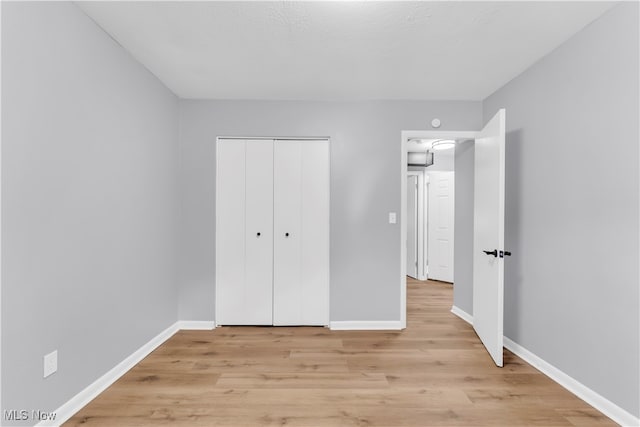 unfurnished bedroom featuring light hardwood / wood-style flooring and a closet