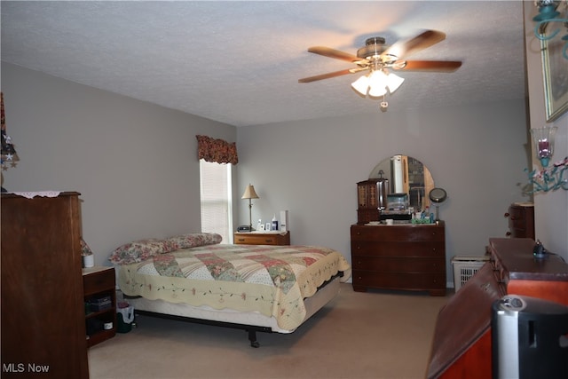 bedroom with ceiling fan, carpet floors, and a textured ceiling