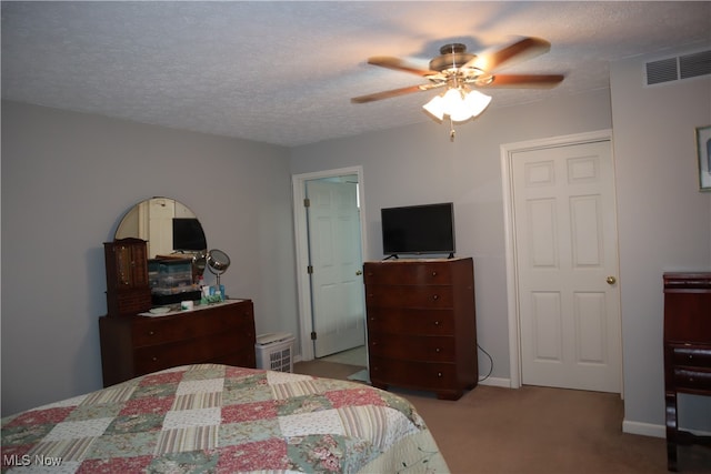 bedroom with a textured ceiling, light colored carpet, and ceiling fan