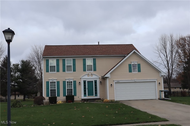 view of front of property featuring a front yard, concrete driveway, fence, and an attached garage