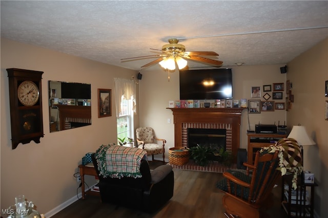 living room featuring a textured ceiling, ceiling fan, wood-type flooring, and a fireplace