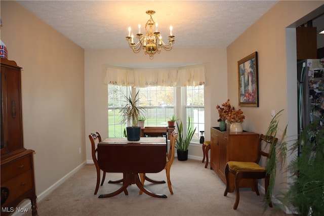 dining room with a chandelier, light colored carpet, a textured ceiling, and baseboards