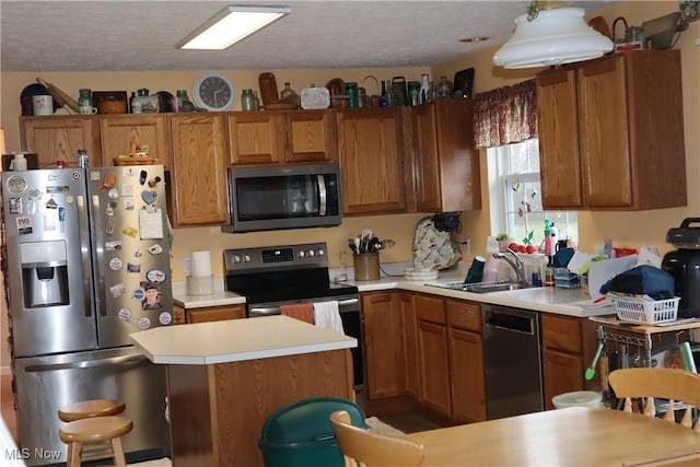 kitchen featuring a textured ceiling, a kitchen island, sink, and appliances with stainless steel finishes