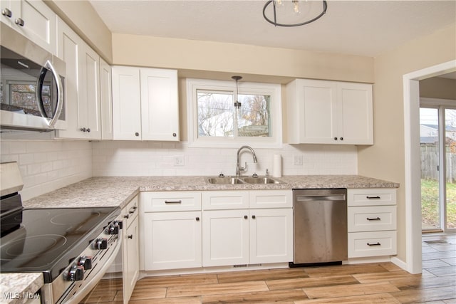 kitchen with light hardwood / wood-style floors, a healthy amount of sunlight, sink, and appliances with stainless steel finishes