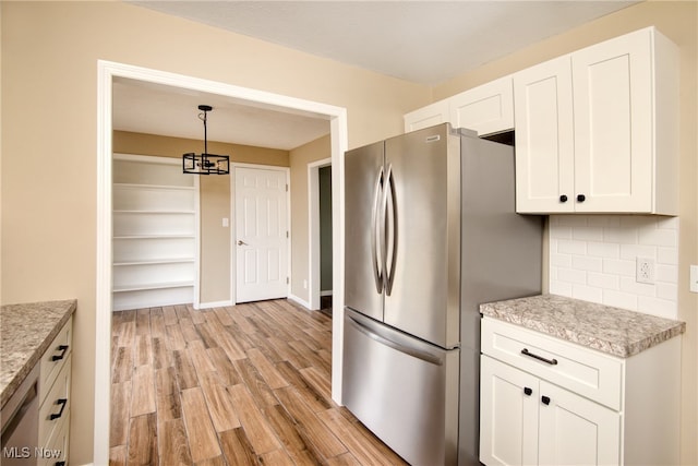 kitchen with backsplash, white cabinets, hanging light fixtures, light wood-type flooring, and stainless steel appliances